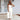 Beige tie-waist sleeveless jumpsuit worn by a smiling woman, showcasing elegant casual summer fashion design with emphasis on waist and neck areas.