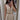 Beige sleeveless V-neck romper with a belted waist, modeled by a woman showing her arm and shoulder.