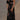 Black floral sheer one-shoulder evening dress with elegant detailing, showcasing a fitted waist, flowing thigh-length design, and a single sleeve, captured in flash photography.