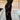 Black floral sheer one-shoulder evening dress displayed on a mannequin, highlighting its elegant design and sheer fabric against a wooden flooring background.