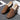 Black textured leather slip-on loafers with zipper for men displayed on a wooden surface, showcasing their sleek design and fashionable appearance.