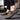 Black textured leather slip-on loafers with zipper for men displayed on a grey background, highlighting the shoe's elegant design and fashionable appeal.