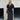 Black V-Neck Open Back Maxi Dress on woman with short sleeves, showcasing shoulder and waist details, accessorized with a bag and eyewear.