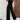 Black velvet sleeveless wide-leg jumpsuit with a smocked bodice, featuring a scooped neck and fitted waist, displayed on a mannequin against a neutral background.
