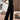 A woman wearing a black velvet sleeveless wide-leg jumpsuit with a smocked bodice, standing and showcasing the fashionable one-piece garment.