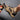 Black waterproof hiking shoes designed for durability and non-slip grip, shown on a person's legs while standing outdoors on a wooden surface.