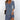 A woman wearing a blue V-neck floral wrap dress with an asymmetric hem and short sleeves.