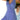 Woman wearing a blue and white geometric V-neck sleeveless A-line summer dress standing with her hand on her waist.