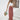 Woman wearing a white lace top and rust palazzo pants, accessorized with a straw hat, carrying a stylish bag.
