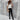 A stylish woman wearing a white blouse, black jeans, black boots, a black hat, and sunglasses.