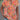 Woman wearing a colorful boho blouse with ethnic patterns, featuring a V-neck, lightweight fabric, and tribal design, showcasing shoulders and arms, with an orange base color.