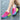 Colorful women's running shoes with a lightweight and breathable design, featuring pink accents, worn by a person outdoors.