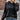 Elegant black lace sleeve sweater for women, styled with jeans. The sweater features intricate lace detailing on the sleeves and is perfect for fall fashion. The woman wearing it is accessorized with sunglasses.