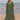 A woman wearing an elegant green V-neck caftan, a lightweight and flowy beach dress, standing on a beach near the water.