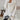 Elegant hooded cardigan in a chic winter fashion style for women, featuring a neutral beige and grey color palette, with a soft collar and long sleeves. The model is standing and showcasing the cardigan's fitted waist and cozy hood.