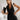 Woman wearing an elegant white sleeveless V-neck belted formal jumpsuit, smiling and posing with hands on hips.