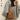 Elegant women's pale green leather mini backpack displayed on a model wearing casual jeans and a jacket, accessorized with a stylish fedora hat.