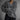 Elegant women's oversized sweater made of soft fur material in a plush, woolen texture, featuring long sleeves, a high collar, and a grey color. The sweater is shown wrapped around a model, highlighting its cozy and fashionable winter design.