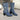 Women's floral blue denim ankle boots with stylish block and high heels, worn by a person sitting on a chair.