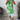 A sleeveless summer tunic top for women featuring a vibrant floral print. The top is displayed in a standing position, highlighting its chic design suitable for fashionable summer wear. The background includes accents of green and white, complementing the floral theme.
