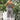 Floral strappy jumpsuit for women worn outdoors, featuring a bohemian summer style with shoulder straps and a fitted waist, paired with casual shoes and eyewear, standing on grass.