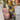 A woman wearing a floral V-neck yellow summer dress, featuring a casual fashion style. The dress has short sleeves and a fitted waist, paired with fashionable eyewear. The dress length reaches the knee, showcasing a stylish and comfortable look suitable for warm weather.