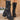 Black chunky platform combat boots for women, featuring a vegan leather material with studded details and lace-up design, shown on a model wearing them up to mid-calf height.