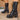 Black chunky platform combat boots with studded detailing and lace-up design, styled for gothic fashion; shown worn on human legs, emphasizing their bold and edgy aesthetic.