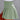 Woman wearing a green smocked summer skirt with elastic waist and ruffles, standing in a casual outdoor setting.