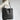 Large caramel handmade leather tote bag for women, featuring a spacious design suitable for work; shown with a shoulder strap and sleek hobo bag style, complemented by a grey color palette.
