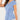 Woman wearing a light blue V-neck twist-front blouse with short sleeves, showcasing an elegant and stylish design.