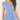 Woman wearing a light blue V-neck twist-front blouse with short sleeves, showing shoulders and arms.
