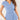 Woman wearing a light blue V-neck twist-front blouse with short sleeves, smiling.