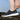 Lightweight breathable slip-on women's sneakers in a water-resistant design, worn by a person dressed in sportswear and denim, with visible legs showing up to the knee, and standing next to a small plant.