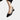 Black leather women's low-heel flats focusing on minimalist design, shown on a model's feet. The shoes are designed for comfort and are suitable for fashion events or everyday wear.