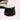 Women's minimalist black leather low-heel flats placed on a textured surface, highlighting their sleek design and comfort-focused construction.