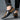 Luxury black leather men's formal shoes featuring a designer checkered pattern, elegantly styled on a person's foot.
