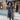 Luxury women's designer down jacket with a fur-hooded parka style, featuring a sleek black design, long sleeves, and elegant silhouette, modeled by a standing person against a white background.
