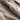 Luxury women's tan suede faux fur winter jacket displayed close-up, highlighting the rich textile texture and soft faux fur lining on the sleeves, against a neutral background.