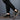 Men's all-black leather low-top sneakers worn with denim jeans, showcasing stylish urban footwear.
