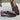 Men's luxury brown leather loafers with buckle, featuring a formal slip-on design and elegant strap detail, displayed on human legs against a neutral background.