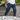Men's navy blue joggers with lightweight, water-resistant fabric, featuring zipper pockets, shown being worn with focus on the waist, knee, and leg areas.