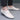 Men's tan leather slip-on loafers shown on a person's feet, highlighting their comfortable and lightweight design. The image focuses on the shoes while being worn, emphasizing their fashion-forward style and suitability for casual occasions. The background is neutral, drawing attention to the footwear.