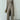 Neutral tone women's elegant fall outfit featuring a ribbed sweater and trousers, with a focus on the joint areas such as shoulders and arms, showcasing the texture and fit around the neck, waist, and legs. The model is standing, emphasizing the outfit's stylish and sophisticated design.