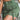 Olive green women's utility mini cargo skirt with a belt and pockets, shown on a model. The skirt is paired with a white top and features a fitted waistline and thigh-length hem.