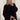 Oversized black knit sweater featuring long sleeves and a relaxed fit, ideal for elegant autumn fashion. The sweater has a wide neckline and is shown on a person with visible shoulder and waist details.