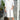 Women's casual peach mid-length spring dress in size 3XL, featuring a lightweight and elegant design, worn by a smiling woman standing indoors near a houseplant and flowerpot.