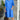 Peach mid-length spring dress for women, casual and lightweight with an elegant design, displayed in a blue variant, size 3XL, worn by a smiling model standing next to a white flowerpot containing a green houseplant, suggesting a bright, spring atmosphere.