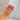 A hand displaying a pink beaded love letter bracelet on the wrist, with the arm partially covered by a sleeve.