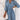 Woman wearing a blue V-neck cinched waist midi dress with a floral pattern, styled for casual summer fashion.